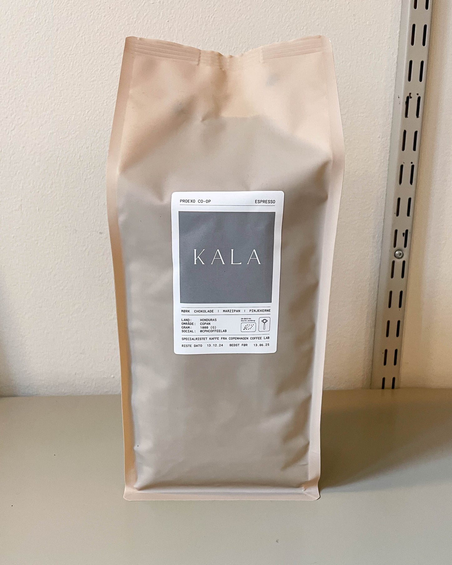 KALA Espresso kaffepose fra Copenhagen Coffee lab på et bord med minimalistisk logo i hvidt, der udstråler elegance og skandinavisk stil.